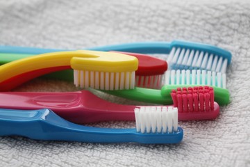 Colorful toothbrushes laying on a white towel. Dental care in family, bathroom, teeth hygiene concept.