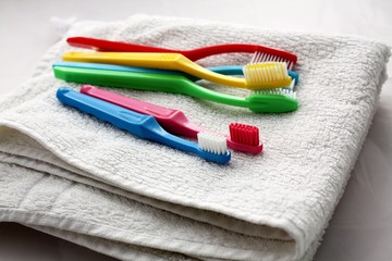 Group of colorful toothbrushes laying on a white towel. Dental care in family, bathroom, teeth hygiene concept.