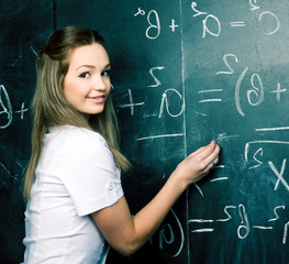 portrait of happy cute student in classroom at blackboard back to school having fun, girl at college