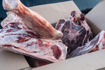 Frozen pieces of deer meat lie in a cardboard box.
