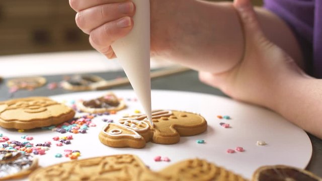 Putting sweet white cream on differents gingerbread cookies. Sweet Christmas holiday cookies with cream. Cooking yummy sweets in the bakery. 4k close up. Slow motion footage. Decoration of cookies.