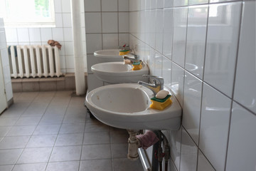 a line of white washbasins in a factory washroom