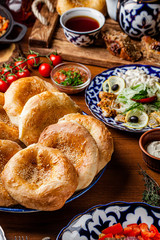 Traditional oriental cuisine. Uzbek cake made of yeast dough with a pattern. Baked in the oven. Serving dishes in Uzbek plates. Copy space, background image