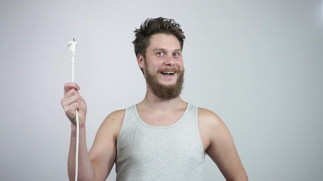 The guy's holding a sparking power cord and smiling