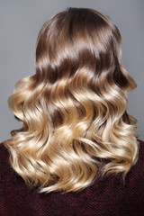 Fototapeta premium Beautiful and Shiny Curly Hair. Fashion Girl With Healthy Long Wavy Hair. Beauty Blonde Woman Back View. Retro