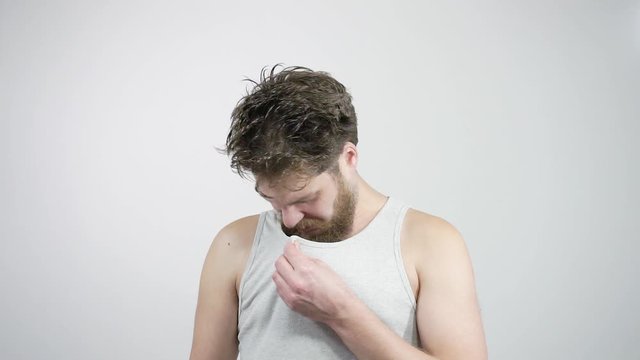 Young bearded man sniffing his armpit, something stinks very bad