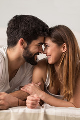 Close up of young couple lying in bed while looking at each other.