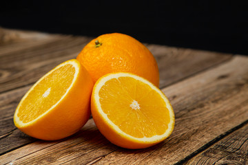 Oranges cut in half on a wooden background.