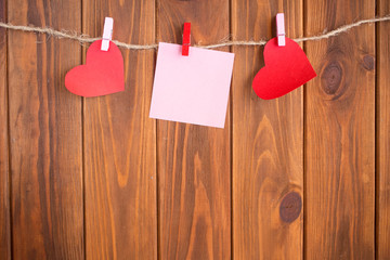 Red hearts are held by clothespins on a jute rope, on a dark wooden background. Copy space.Valentine's Day