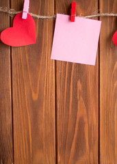 Red hearts are held by clothespins on a jute rope, on a dark wooden background. Copy space.Valentine's Day