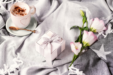Having a cup of coffee with chocolate, gift box and flowers eustoma on blanket in bed. Holiday concept