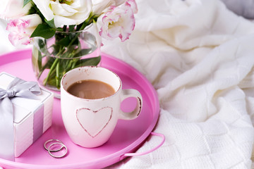 A tray with a cup of coffee, gift box, flowers and rings on the bed. Valentine's Day Wedding Offer