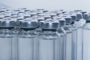 Glass medical ampoule vial for injection. Medicine is dry white drug penicillin powder or liquid with of aqueous solution in ampulla. Close up. Bottles ampule with aluminum cap on backgrounds gray.