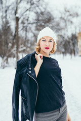 Beautiful winter view with snowfall - a happy and dreamy young attractive blonde in a black t-shirt outside in the frost