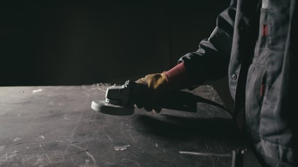 Forge workshop. Smithy manual production. Industrial worker using angle grinder and cutting steel....