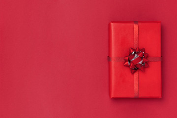 New Year and Christmas composition. Gift box on red paper background. Top view, flat lay, copy space