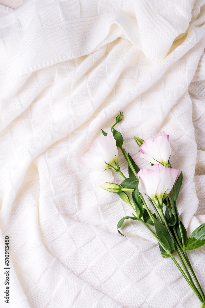 Wall mural Flowers eustoma on white blanket background, flat lay copy space. Holiday concept