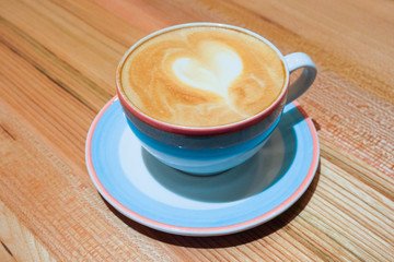 A nice Cup of cappuccino with heart pattern. Drawing on coffee. The concept of Valentine's day. Cup of cappuccino with nice latte art on wooden surface. Background for coffee shop
