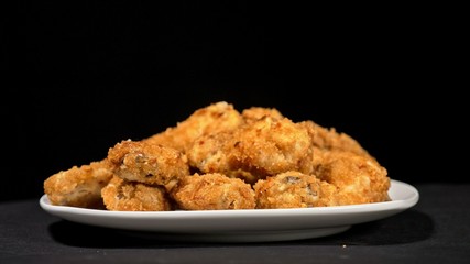 Cool beautiful fresh juicy cooked chicken wings in breading. Buffalo wings spread on food white plate in table. Very tasty and beautiful. Cooking with deep fryer fry machine.