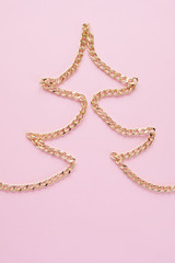 a gold chain laid out in the shape of a x-mas tree on a pink background