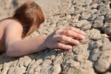 Woman lying on cracked land with focus on hand