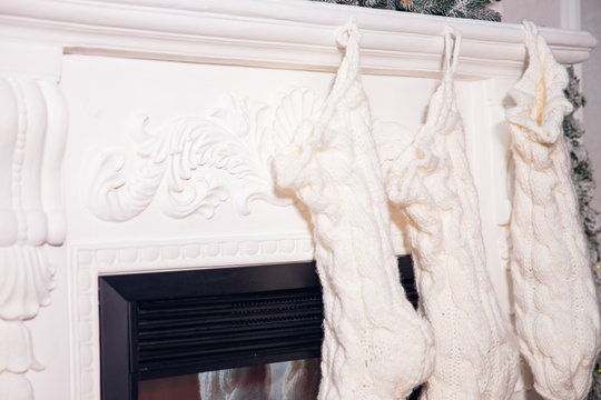 White knitted wool socks for Christmas gifts on fireplace
