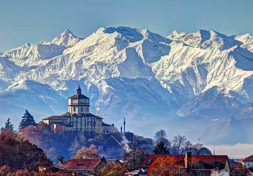 Panoramic view on the church of Monte Cappuccini in Turin, Piedmont, Italy, surrounded by snowy Alps mountains in a clear blue sky winter morning