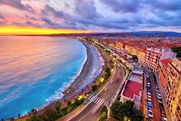 Papier Peint photo autocollant Nice Vue impressionnante sur le coucher de soleil sur le front de mer de Nice depuis la colline du château, avec un ciel et des nuages tumultueux et une lumière chaude