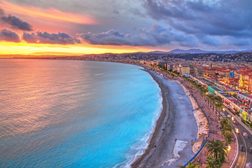 Vue impressionnante sur le coucher de soleil sur le front de mer de Nice depuis la colline du château, avec un ciel et des nuages tumultueux et une lumière chaude