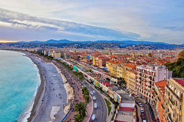 Impressive sunset view of Nice sea waterfront from the castle hill, with tumultuous sky and clouds, and warm light