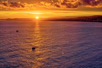 Spectacular fiery red and orange sunset on the Nice coast with silhouette of boats on the sea