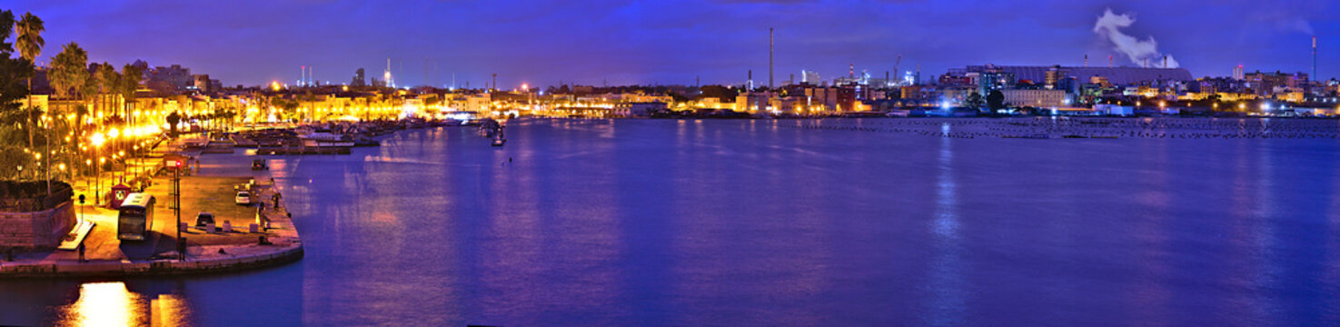 Panoramic view at blue hour on the Old Town of Taranto, Puglia, Italy, and in the background the highly polluting steel plant, former Ilva, now ArcelorMittal