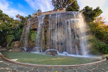 Cascade Du Casteu is a historical artificial waterfall in the Castle Garden of Nice, France. Winter view with blue sky