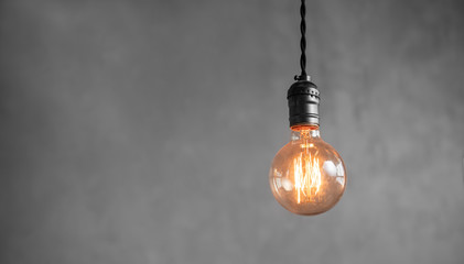Edison retro lamp incandescent bulbs on gray plaster wall background in loft. Concept Vintage...