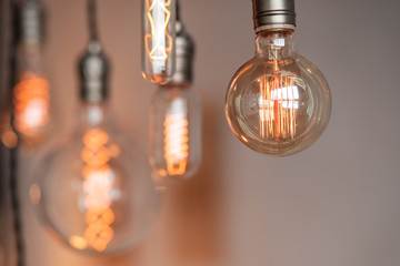 Edison retro lamp incandescent bulbs on gray plaster wall background in loft. Concept Vintage style. Copy space