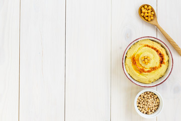 Hummus in a bowl on a wooden table. Horizontal orientation, copy space.