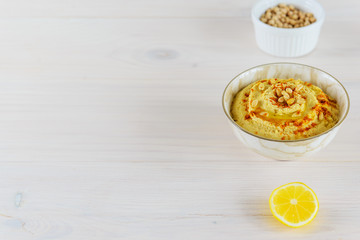 Hummus in a bowl on a wooden table. Horizontal orientation, copy space.