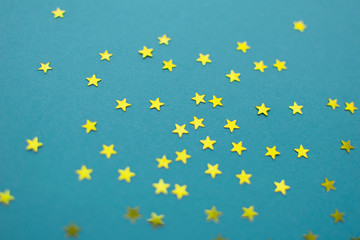 Modern festive flat lay background with gold stars glitter on blue paper backdrop. Minimalist design.