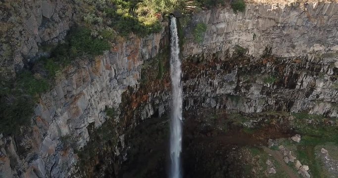 4k aerial flying away from waterfall on huge cliff