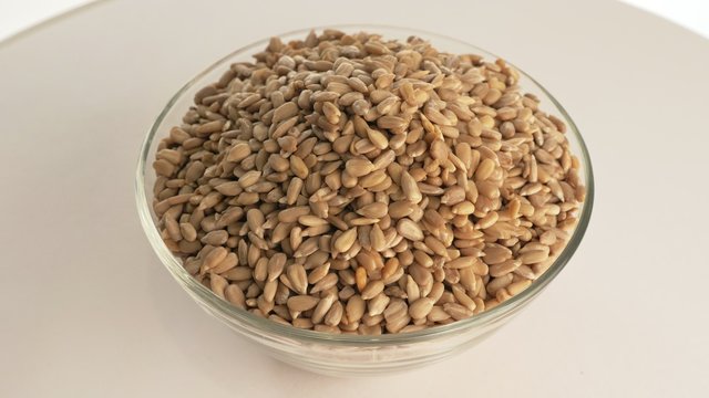Nuts sunflower rotate are on a table in a plate. Snack in transparent dish on an isolated white background are spinning moving. Delicious and healthy protein-rich diet food.