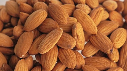 Nuts almond rotate are on a table in a plate. Snack in transparent dish on an isolated white background are spinning moving. Delicious and healthy protein-rich diet food.