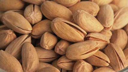 Nuts pistache rotate are on a table in a plate. Snack in transparent dish on an isolated white background are spinning moving. Delicious and healthy protein-rich diet food.
