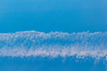 A band of white clouds on a blue sky background