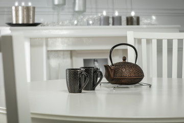 White wooden table with kettle of tea and home interior 