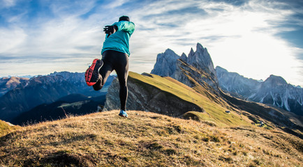 Young man in sport trail clothes running on Seceda mountain peak at sunrise. Puez Odle, Trentino,...