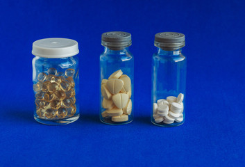 Different  medical pills in glass jar on a blue  background. Viral infection season. Traditional  medicine, healthcare and wellness concept.