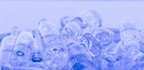 Glass medical ampoule vial for injection. Medicine is liquid sodium chloride with of aqueous solution in ampulla. Close up. Bottles ampule multicolor on background color and water. Human plasma.