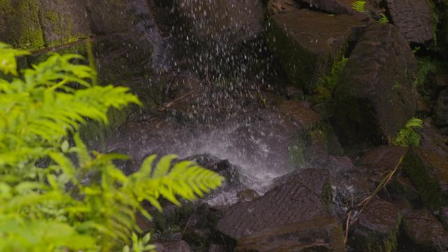 Upward panning shot of a minature man made waterfall running onto wet rocks