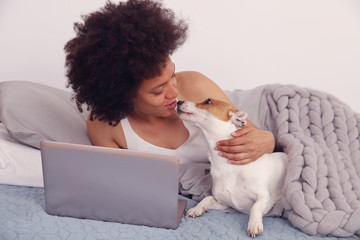 Cozy woman covered with warm blanket using laptop, hugging her dog. Relax, carefree, comfort...