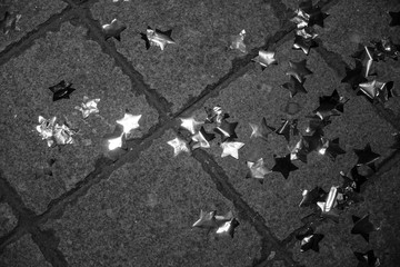 Asphalt background texture. Black and  white photo of shiny tinsel star shaped decorations atop...